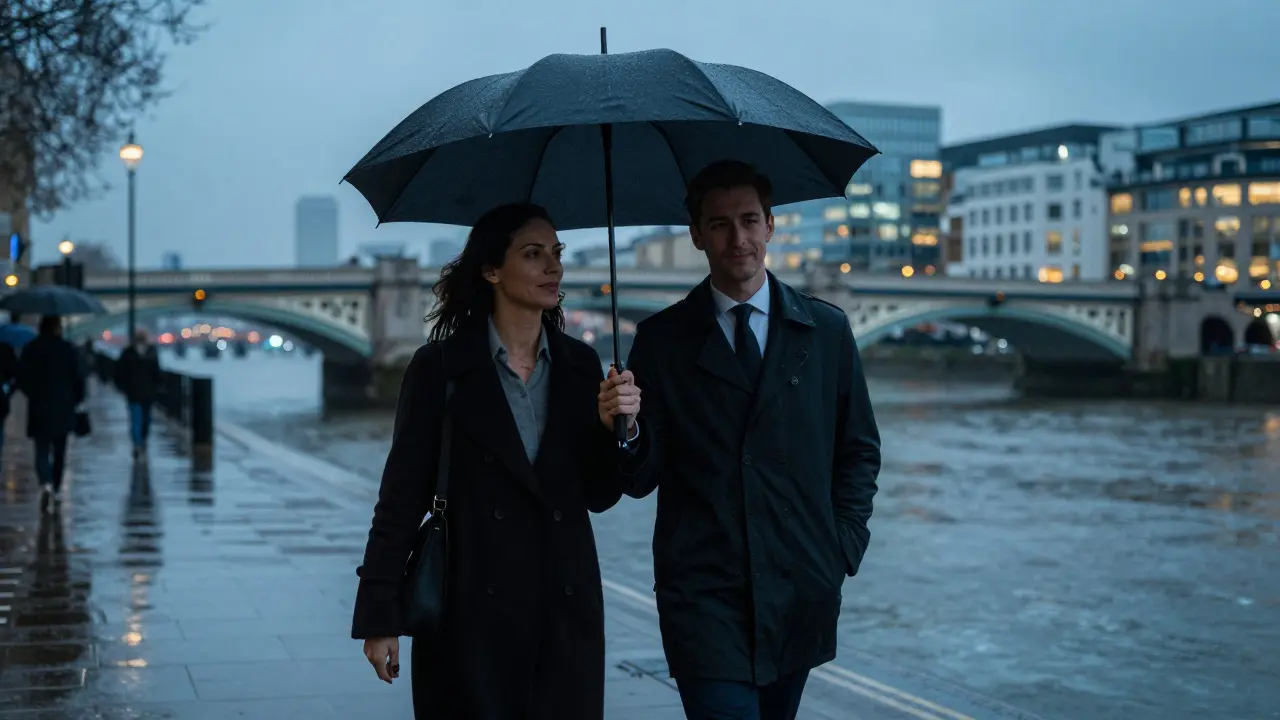 A man and woman walking together under an umbrella along the Thames at dusk, city lights glowing behind them.